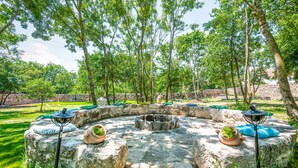 A circular stone fire pit surrounded by seating with cushions and a stone wall in the background. - Gorgeous home in Imotski (Imotski)