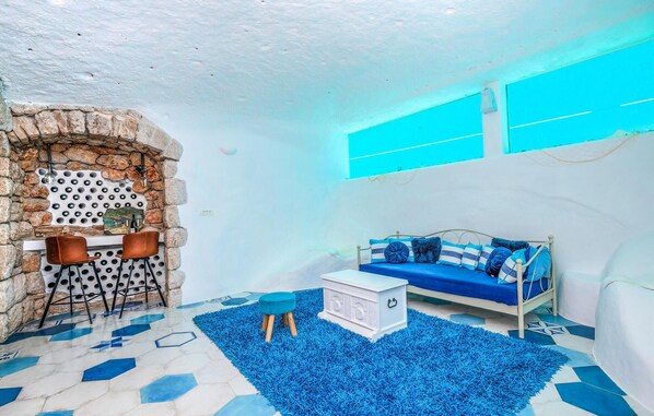 A room with a stone wall, a blue sofa, a white chest of drawers, and a blue rug. - Gorgeous home in Imotski (Imotski)