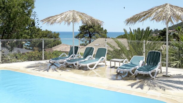 A poolside area with lounge chairs and umbrellas, a clear view of the sea, and a fenced perimeter. - Stunning  villa for 6 people with pool, WIFI, A/C, TV and terrace (Tarco)