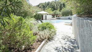 A swimming pool surrounded by lush greenery, a small building with a pergola, and a stone pathway. - Lovely apartment for 10 people with A/C, WIFI, pool, TV, patio, pets allowed and panoramic view (Pierraggi)