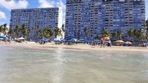 Una playa con un hotel grande al fondo.