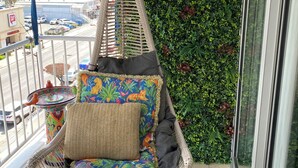 Una silla colgante con un cojín de colores y un cartel que dice 'BEACH' al fondo.