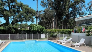 A swimming pool with white lounge chairs and a fenced area.