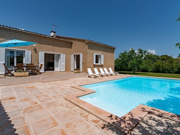 A house with a swimming pool, outdoor furniture, and a garden.