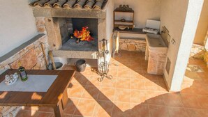 A rustic outdoor kitchen with a stone fireplace, a wooden table, and a stone oven. - Stunning private villa for 6 people with private pool, A/C, WIFI, TV and terrace (Pazin)