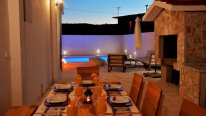 An outdoor dining area with a view of the sea, a stone fireplace, and a beach chair. - Beautiful home in Pozorac (Pozorac)