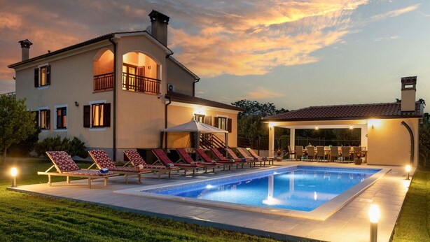 A two-story house with a swimming pool, outdoor seating, and a covered patio area.