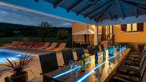 An outdoor dining area with a pool, lounge chairs, and a covered patio.
