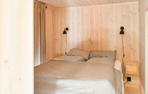 Ein Schlafzimmer mit Holzwänden, einem Bett, zwei Nachttischlampen und einem Nachttisch.