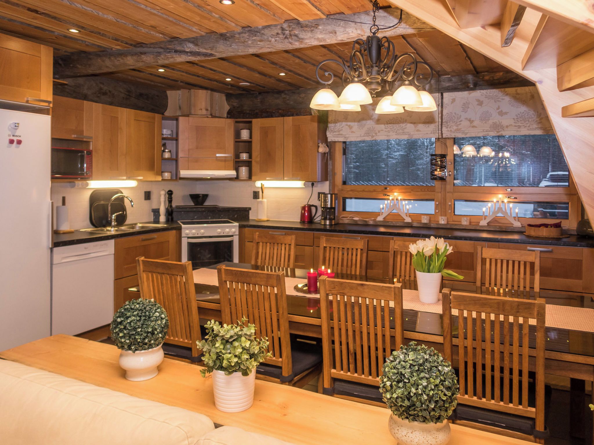Una cucina accogliente con mobili in legno, un tavolo da pranzo con sedie e un lampadario.