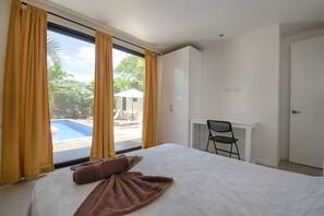 Ein Hotelzimmer mit Bett, Schreibtisch und Blick auf einen Außenpool.
