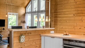 Een moderne keuken met houten wanden, een inbouwoven en een raam met uitzicht op groen.