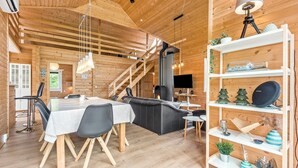 Een knus interieur van een blokhut met een eethoek, bank en een boekenplank.