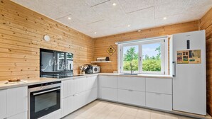 Een moderne keuken met houten lambrisering, een ingebouwde oven, een koffieapparaat en een koelkast.
