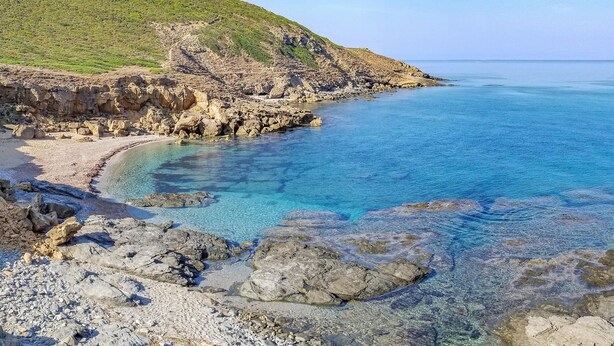 Un paysage côtier caractérisé par un terrain rocheux et des eaux d’un bleu limpide.