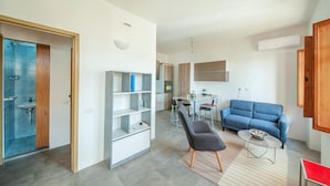 Un salon moderne comprenant un canapé, une table basse et un coin repas avec des chaises.