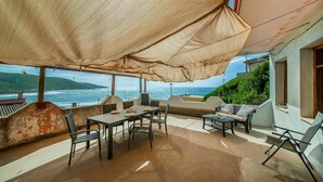 Une terrasse avec une table et des chaises, donnant sur la mer.
