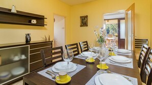 A dining area with a wooden table set for four, yellow and white tableware, and a wooden cabinet with decorative items. - Beautiful private villa for 8 guests with A/C, internet, private pool, TV, terrace and pets allo... (Buzet)