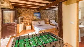 A cozy room with a stone wall, wooden beams, a bed with two pillows, a small table, and a foosball table. - Beautiful private villa for 8 guests with A/C, internet, private pool, TV, terrace and pets allo... (Buzet)