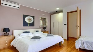 A bedroom with a bed, bedside tables, a wardrobe, and an air conditioning unit. - Wonderful  villa for 8 people with A/C, WIFI, TV, terrace and pets allowed (Umag)