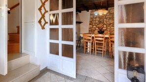 A room with a stone wall, a wooden staircase, and a dining area with chairs and a table. - Wonderful  villa for 8 people with A/C, WIFI, TV, terrace and pets allowed (Umag)
