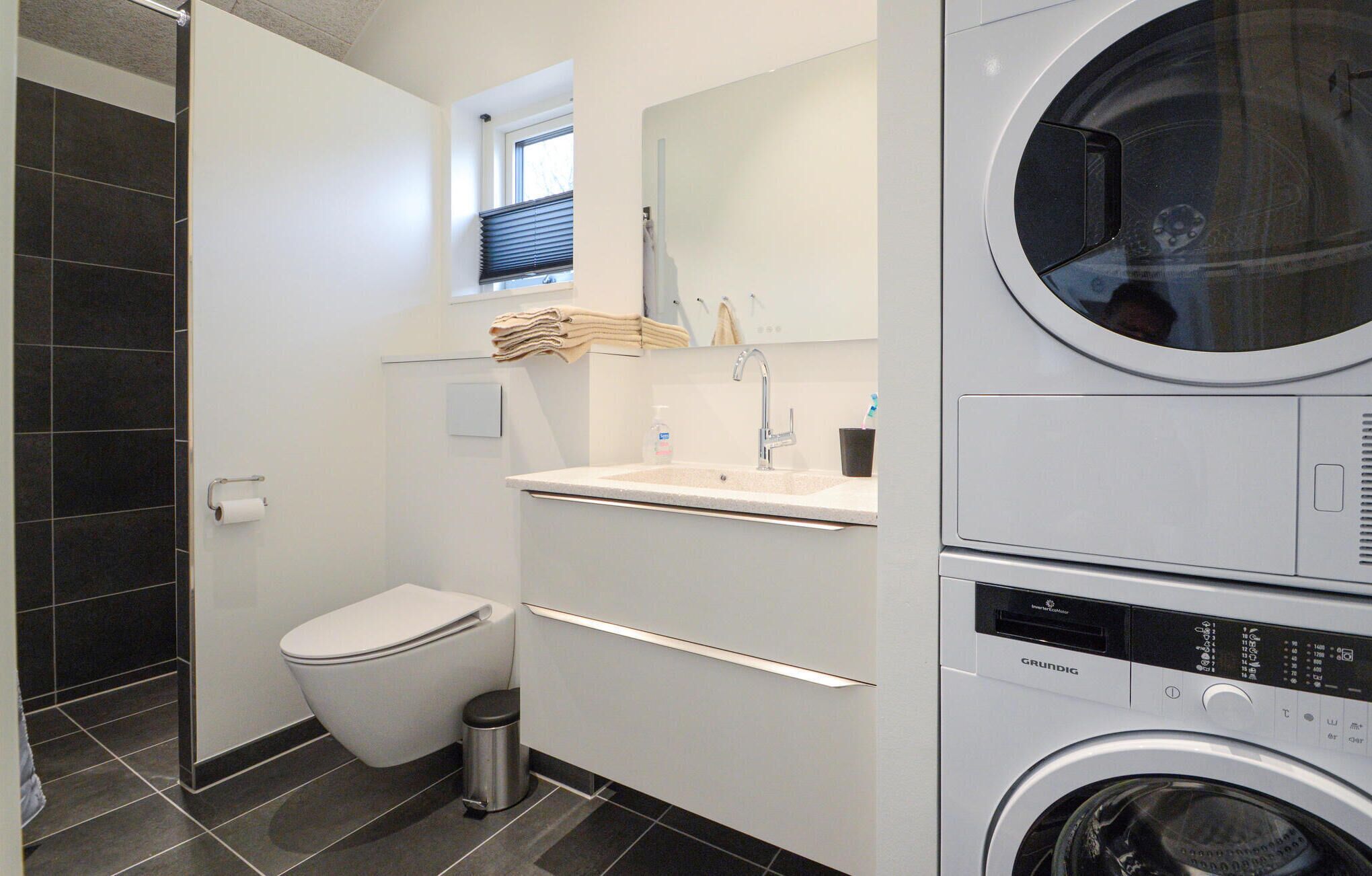 Ein modernes Badezimmer mit Toilette, Waschbecken und gestapelten Handtüchern.