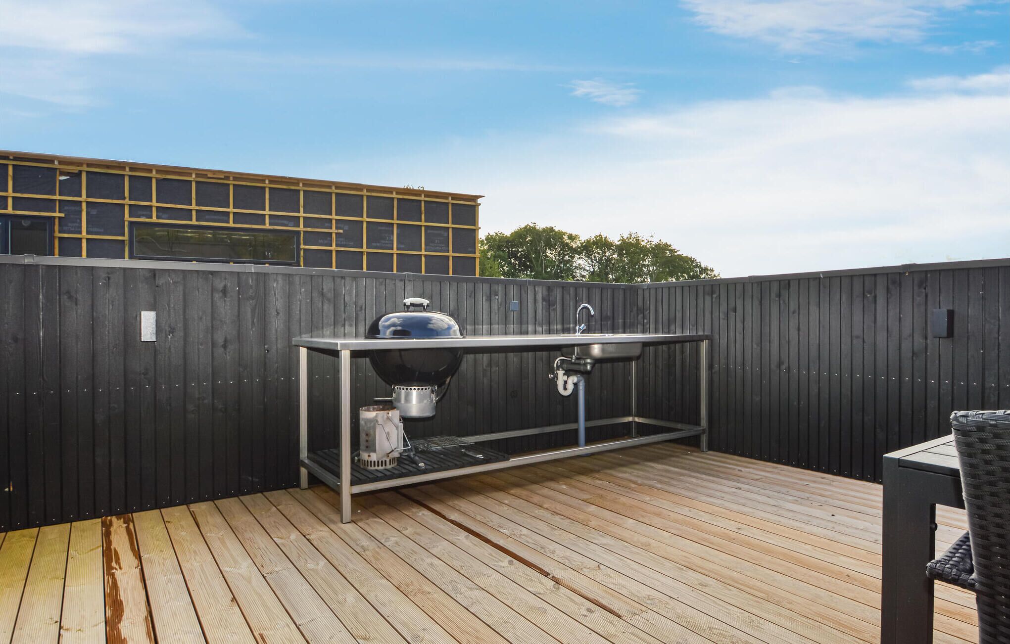 A rooftop deck with a barbecue grill, sink, and a metal table.