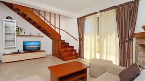 A living room with a wooden staircase, a TV on a cabinet, a sofa, and a coffee table. - Beautiful private villa for 7 guests with A/C, WIFI, TV, terrace and pets allowed (Umag)