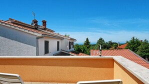 A terrace with two white lounge chairs, a view of a building with a red-tiled roof, and a clear blue sky. - Beautiful private villa for 7 guests with A/C, WIFI, TV, terrace and pets allowed (Umag)