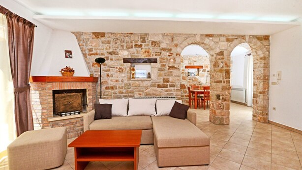 A living room with a stone wall, a fireplace, a sofa, and a coffee table. - Beautiful private villa for 7 guests with A/C, WIFI, TV, terrace and pets allowed (Umag)