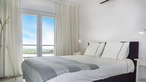 A bedroom with a large bed, white curtains, a nightstand, and a view of the outdoors. - Beautiful home in Trullent (Trullent)