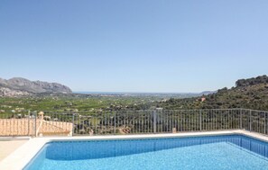 Piscina con vista a un paisaje montañoso y un pueblo lejano.