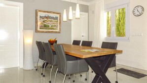 A modern dining room with a wooden table, grey chairs, pendant lights, a framed painting, and a clock on the wall. - Beautiful home in Trullent (Trullent)