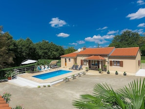 Une maison à deux étages avec une piscine, un espace salon extérieur et un jardin.