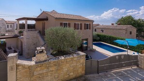 Une villa avec piscine, des murs en pierre et une pergola.