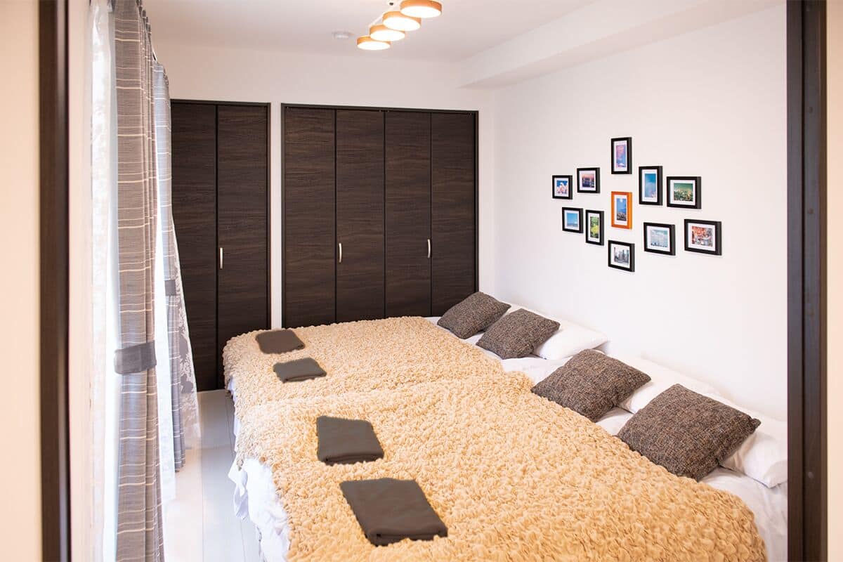 A bedroom with a large bed, dark wooden wardrobe, and a wall decorated with framed pictures.