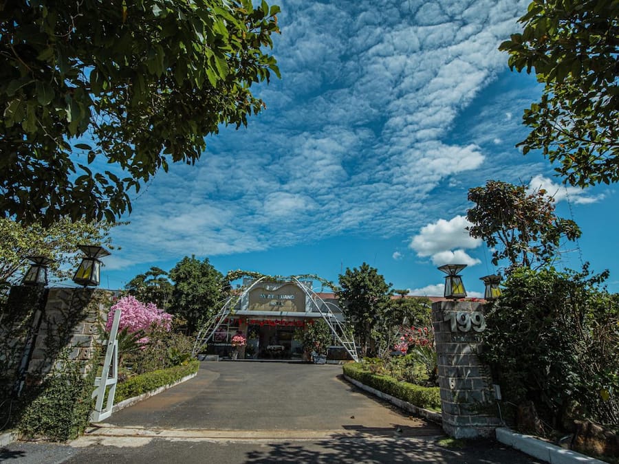 A hotel entrance with a covered driveway, stone walls, and a clear blue sky.