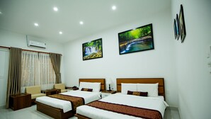 A hotel room with two beds, a sofa, a nightstand, and a window with curtains. - Nhat Quang Hotel (1 Bao Loc)