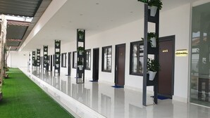 A modern hotel corridor with a green artificial lawn, potted plants, and a clean, reflective floor. - Nhat Quang Hotel (1 Bao Loc)