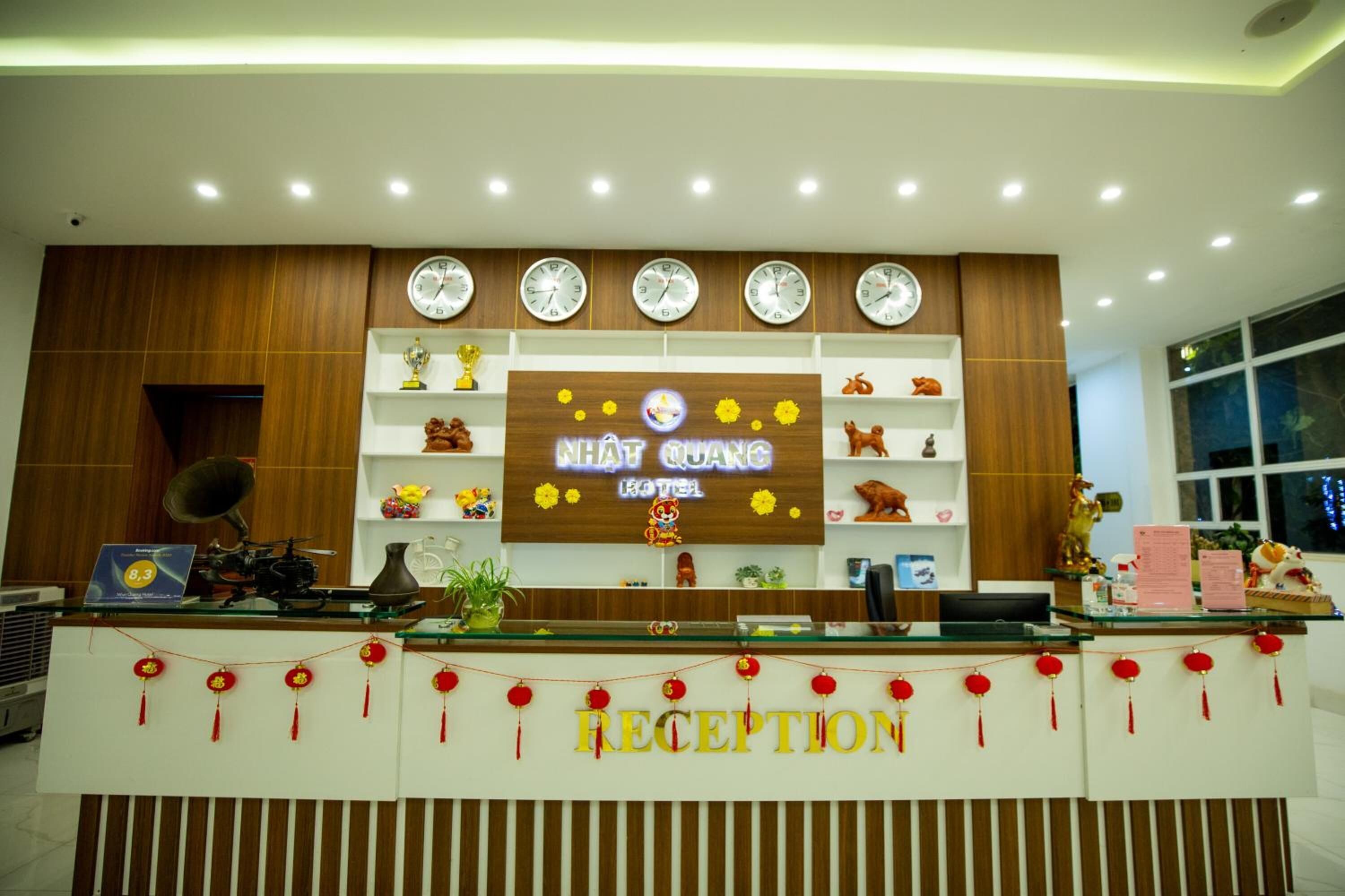 A reception desk with a sign reading "WHAT QUANG HOTEL" and a clock above it.