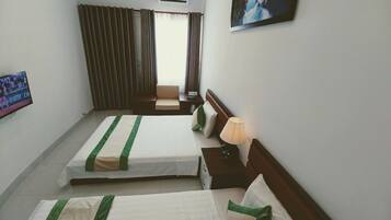 A hotel room with two beds, a TV, a painting, and a window with curtains.