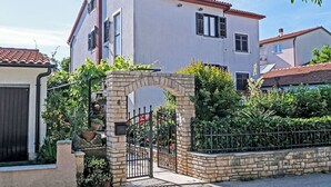 A two-story house with a stone archway entrance, a gated driveway, and a red-tiled roof. - Nice apartment for 7 people with A/C, hot tub, WIFI, TV and patio (Vinkuran)