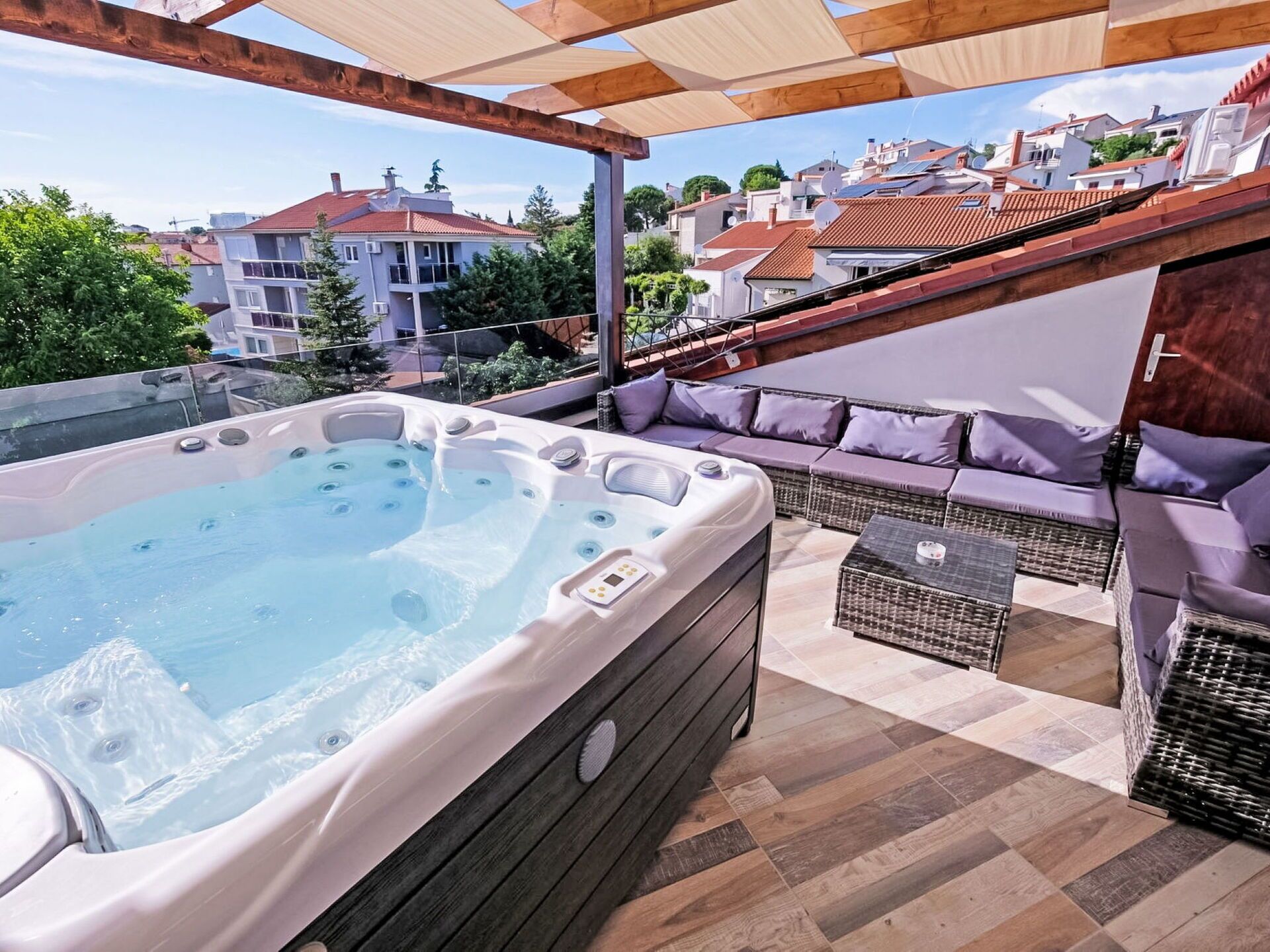 A rooftop terrace with a hot tub, outdoor seating, and a view of the neighborhood.