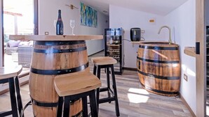 A modern kitchen with wooden barrels as stools, a wine bottle, and glasses on a bar counter. - Nice apartment for 7 people with A/C, hot tub, WIFI, TV and patio (Vinkuran)