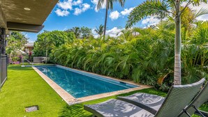 Una piscina rodeada de exuberante vegetación y un cielo azul cristalino.