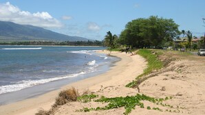 Una playa con arena, algunas personas y una montaña al fondo.
