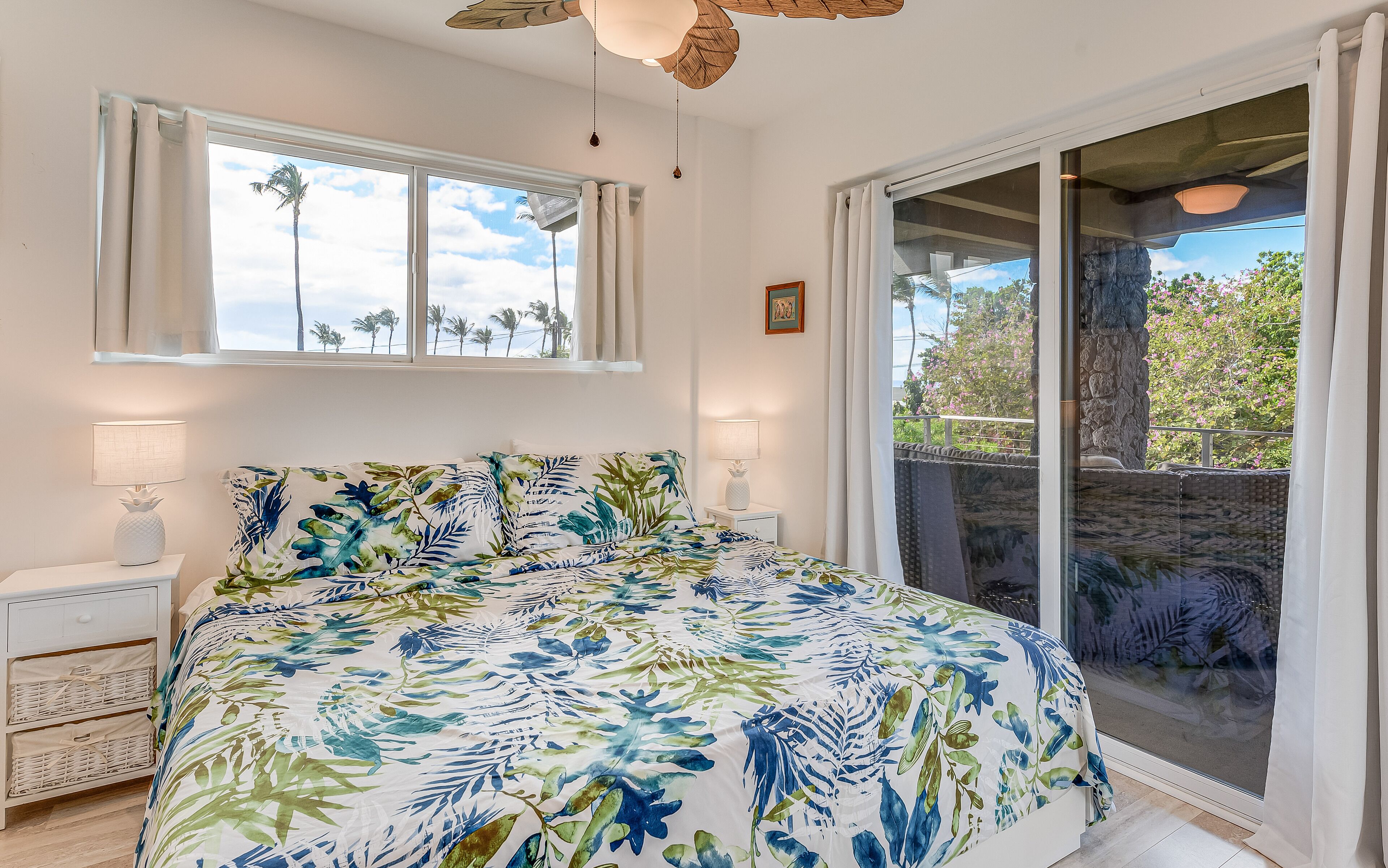 A bedroom with a bed, two bedside tables, a window, and a view of the outdoors.