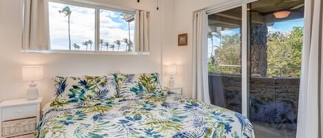 A bedroom with a bed, two bedside tables, a window, and a view of the outdoors.