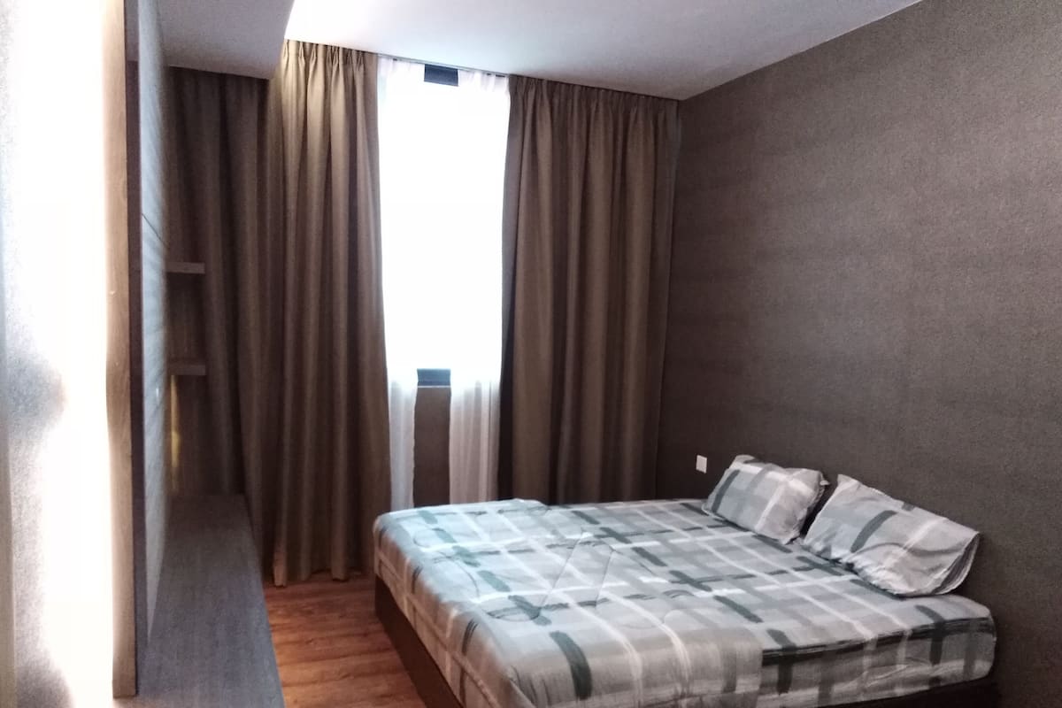 A bedroom with a bed, curtains, and a window.