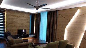 Una sala de estar moderna con televisor de pantalla plana, dos sofás, una mesa de centro y un ventilador de techo.